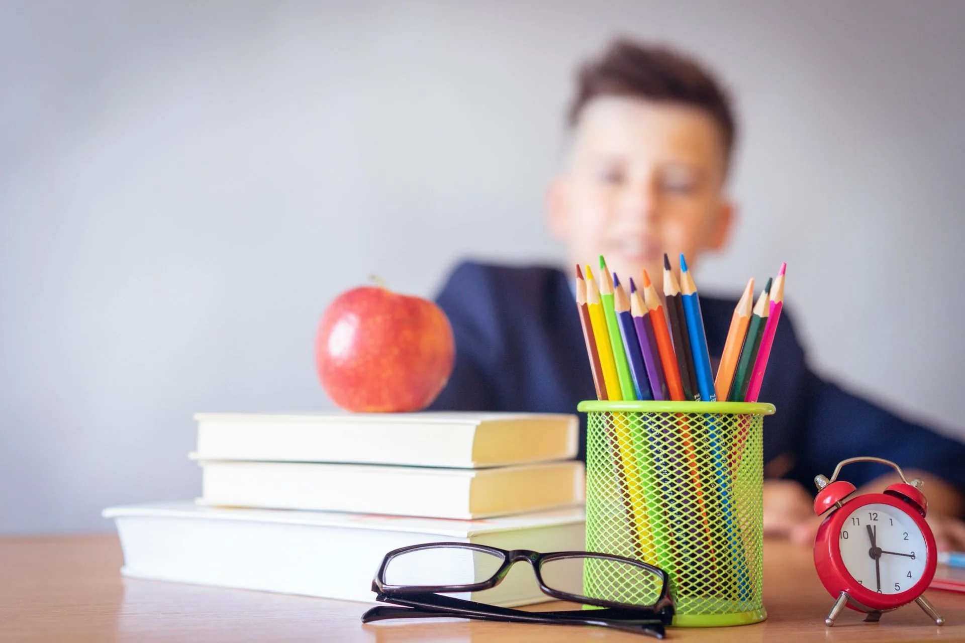 Skolepult med blyanter, eple og bøker